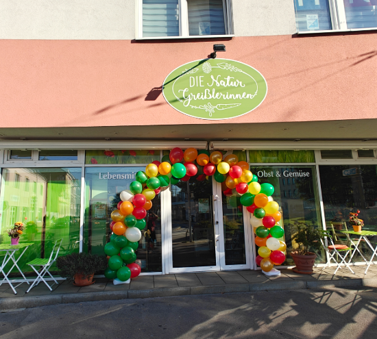 Geschäft der Naturgreißlerinnen von außen mit einem bunten Luftballonbogen